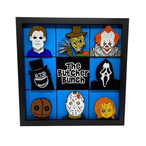 May include: A black framed shadow box with a blue background and nine different horror movie character pins. The pins include Jason Voorhees, Freddy Krueger, Michael Myers, Leatherface, Chucky, Ghostface, Pennywise, and the Creeper. The title "The Butcher Bunch" is printed in white letters on a black background.
