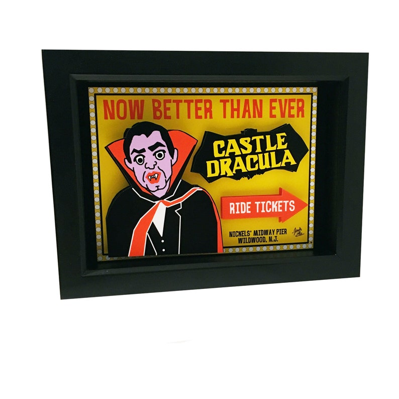 May include: A vintage-style sign advertising a "Castle Dracula" ride at a carnival or amusement park. The sign features a cartoon vampire with a red cape and fangs, and the text "Now Better Than Ever" in yellow letters. The sign is framed in black and has a red arrow pointing to the right with the text "Ride Tickets".