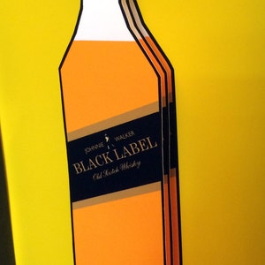K&ouml;nnte beinhalten: Eine Flasche Johnnie Walker Black Label 12 Jahre alter,  verschnittener Scotch Whisky mit gelbem Hintergrund und Signatur.