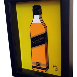 K&ouml;nnte beinhalten: Ein gerahmter Druck einer Flasche John Walker & Sons Black Label 12 Jahre alter Blended Scotch Whisky auf gelbem Hintergrund. Der Druck ist signiert mit "Josh 2015".