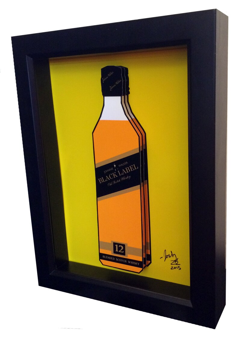 K&ouml;nnte beinhalten: Ein gerahmter Druck einer Flasche John Walker & Sons Black Label 12 Jahre alter Blended Scotch Whisky auf gelbem Hintergrund. Der Druck ist signiert mit "Josh 2015".