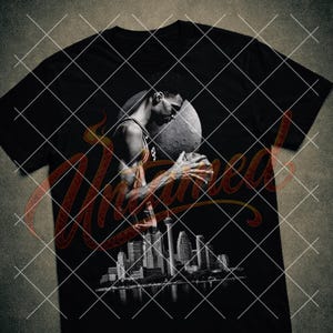 Könnte beinhalten: Schwarzes T-Shirt mit einem Graustufenbild eines Basketballspielers, der einen Basketball hält, mit einer Stadtlandschaft darunter. Das Design beinhaltet einen stilisierten Mond und eine dekorative Schriftüberlagerung.