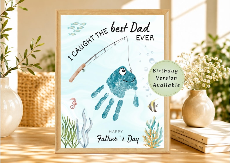 May include: A framed print featuring a teal handprint shaped like a fish on a light blue background. The text reads I CAUGHT THE best Dad EVER and HAPPY Father's Day. A fishing rod, small fish, seahorse, and seaweed are illustrated.
