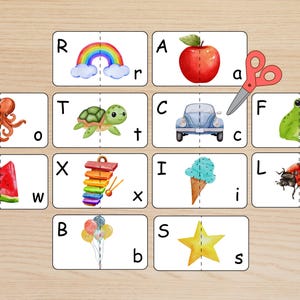 May include: A set of rectangular educational cards featuring uppercase and lowercase letters paired with watercolor illustrations including a rainbow, apple, octopus, turtle, car, frog, watermelon, xylophone, ice cream, ladybug, balloons, and star.