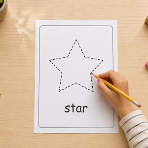 May include: A white rectangular worksheet featuring a black dashed outline of a five-pointed star and the word star printed in black lowercase letters below the shape. A yellow pencil is positioned on the paper to trace the star outline.