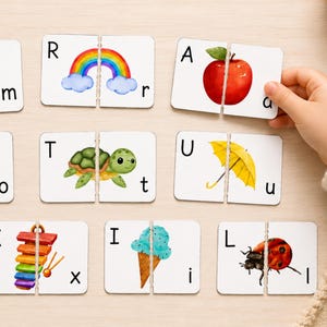May include: A set of white rectangular educational matching cards featuring colorful watercolor illustrations of a monkey, rainbow, apple, octopus, turtle, umbrella, xylophone, ice cream, and ladybug paired with uppercase and lowercase letters.
