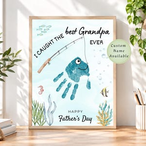 May include: A rectangular print featuring a blue handprint transformed into a fish with a fishing rod. The text reads I CAUGHT THE best Grandpa EVER and HAPPY Father's Day. A small green circle states Custom Name Available.