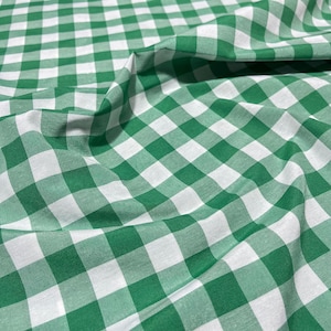 Può includere: Tessuto a quadri verdi e bianchi. Il tessuto è piegato, mostrando la trama e il motivo. Il motivo è un classico design a quadretti, con quadrati verdi e bianchi uniformemente distanziati.