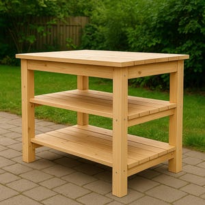 May include: A light-colored wooden outdoor kitchen island with a rectangular top and two lower shelves. The island is constructed from planks of wood and is designed for outdoor use. The shelves provide additional storage space. The island is set on a brick patio.