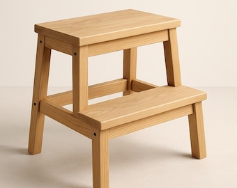 May include: A two-step wooden step stool. The stool is made of light-colored wood and has a rectangular top step and a lower step. The legs are sturdy and angled for stability. The step stool is designed for reaching higher places.