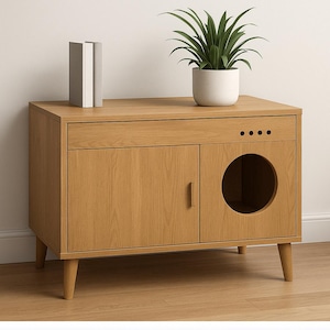 May include: A light oak cat litter box enclosure with a round entry hole and a cabinet door. The top has a drawer and a potted plant. Two books are on top. The enclosure is on four angled legs.