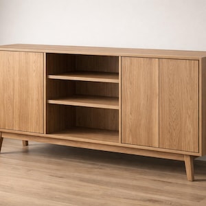 Op de afbeelding: Een licht houten dressoir met twee deuren en open schappen. De kast heeft een modern design uit het midden van de eeuw met schuine poten en een natuurlijke houtnerf afwerking. De kast biedt opbergruimte.