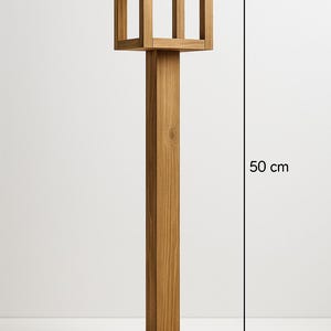 Op de afbeelding: Een houten buitenlantaarn met een vierkante basis van 40 cm bij 10 cm. De lantaarn is 50 cm hoog en heeft een vierkante bovenkant met open zijkanten. De lantaarn is gemaakt van lichtbruin hout.