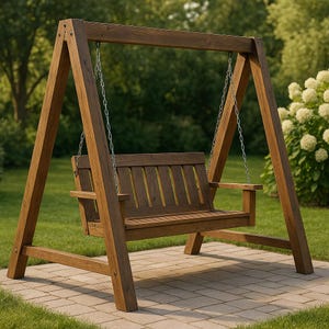 Puede incluir: Un columpio de madera marrón suspendido por cadenas metálicas de un marco en A de madera. El columpio tiene respaldo de listones y reposabrazos. El conjunto está sobre un patio de ladrillos con césped y árboles al fondo.