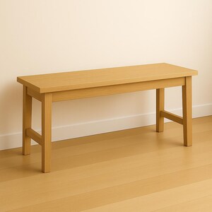 May include: A light brown wooden bench with a rectangular seat and four sturdy legs. The bench is approximately 48 inches long and is made of solid wood. The design is simple and functional, suitable for various settings.