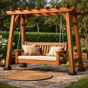 May include: A wooden swing set with a pergola-style top. The swing has a beige cushion and several throw pillows. The frame is made of stained wood and is supported by sturdy posts. A round, woven rug sits on the stone patio in front of the swing.