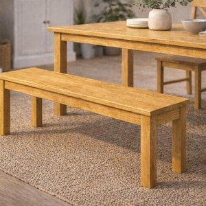 Könnte beinhalten: Ein hellbraunes Esszimmerset aus Holz mit einem rechteckigen Tisch, einer Bank und Stühlen. Der Tisch ist mit einer Schüssel, Tellern und einer Vase gedeckt. Die Möbel stehen auf einem neutral getönten Teppich, was eine warme Atmosphäre schafft.