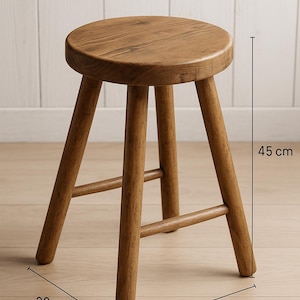 May include: A wooden stool with a round seat and three angled legs. The stool is made of light brown wood and measures 17.7 inches high, 11.8 inches wide, and 17.7 inches long.