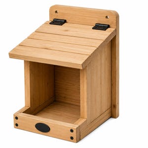 May include: A light brown wooden birdhouse with a slanted roof attached by two black metal hinges. The structure features a flat back panel with two pre-drilled holes for mounting and a small black oval plaque centered on the front lower edge.