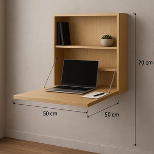 Puede incluir: Un escritorio de madera montado en la pared con una superficie de trabajo plegable. El escritorio mide 50 cm de ancho y 50 cm de profundidad, con una altura total de 70 cm. Cuenta con una estantería con una pequeña planta, libros y un portátil. Un bolígrafo y un bloc de notas están sobre el escritorio.