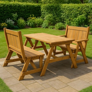 Op de afbeelding: Een houten picknicktafel met twee bijpassende banken. De tafel heeft een rechthoekig blad en schuine poten. De set is gemaakt van lichtgekleurd hout en staat op een stenen terras in een tuin.