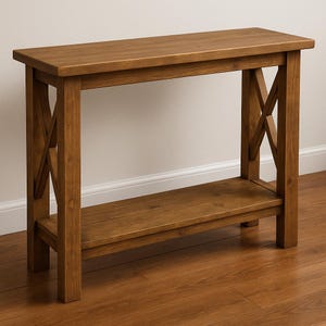 Peut inclure: Une console en bois marron avec un design en forme de X sur les côtés. La table a un plateau rectangulaire et une étagère inférieure pour le rangement. La table est en bois massif et a une finition naturelle.