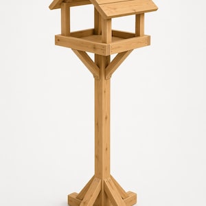 May include: A freestanding wooden bird feeder. It features a pitched roof, a square feeding platform, and a sturdy, square post base. The natural wood construction gives it a rustic appearance. The height is approximately 150 cm.