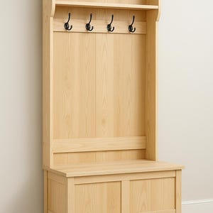 Puede incluir: Un mueble de recibidor de madera clara con banco, almacenamiento y estante superior. Cuenta con cuatro ganchos negros para colgar objetos. La veta de la madera es visible, y el diseño es sencillo y funcional.