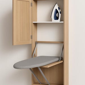 May include: A light wood wall-mounted ironing centre. It includes a fold-out ironing board with a grey cover, a shelf, and a cabinet door. A white and blue iron is on the shelf. The unit is designed to save space, ideal for smaller homes.