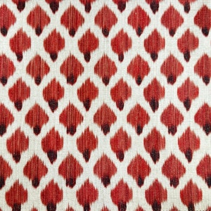 May include: Red and white fabric with a repeating pattern of stylized teardrop shapes. The fabric has a textured, woven appearance.