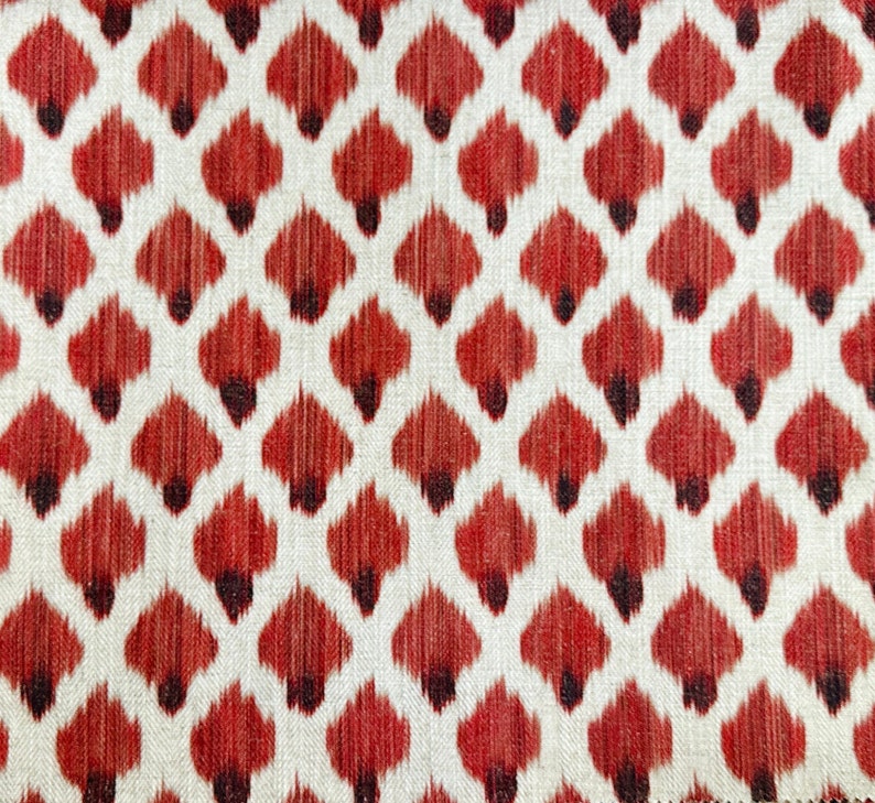 May include: Red and white fabric with a repeating pattern of stylized teardrop shapes. The fabric has a textured, woven appearance.