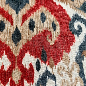 May include: Close-up of a fabric with a red, brown, black and white ikat pattern.