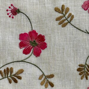 May include: A white fabric with embroidered pink flowers and brown leaves. The fabric has a subtle linen texture.