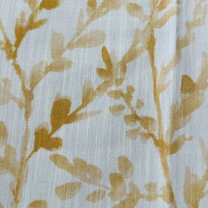May include: White fabric with a subtle texture featuring a repeating pattern of gold leaf branches. The branches are stylized and have a faded, watercolor-like appearance.