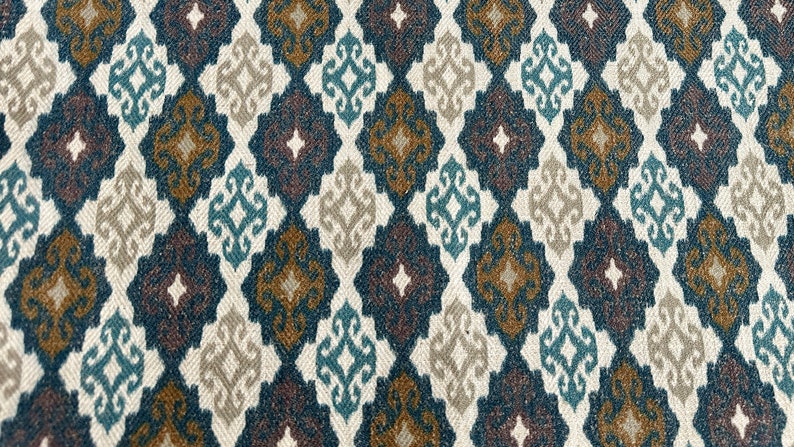 May include: A fabric with a repeating pattern of diamond shapes in shades of brown, blue, and white. The pattern is intricate and features a small floral design within each diamond.