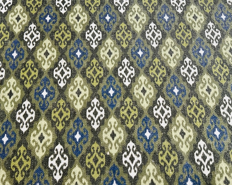 May include: A fabric with a repeating pattern of green, blue, and white diamond shapes. The diamonds have a stylized floral design inside.