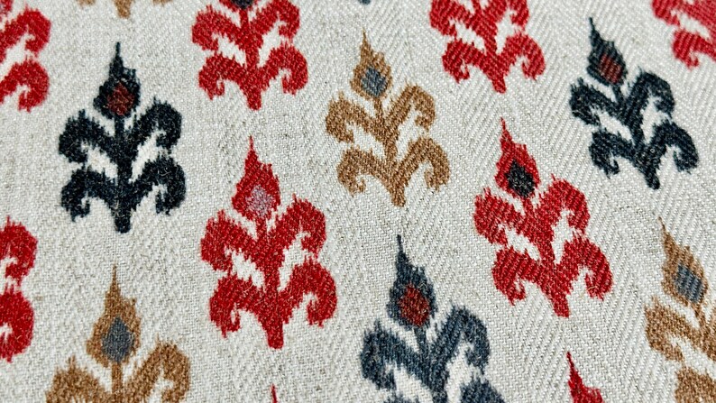 May include: A close-up of a fabric with a repeating pattern of stylized floral motifs in red, black, and brown on a white background.