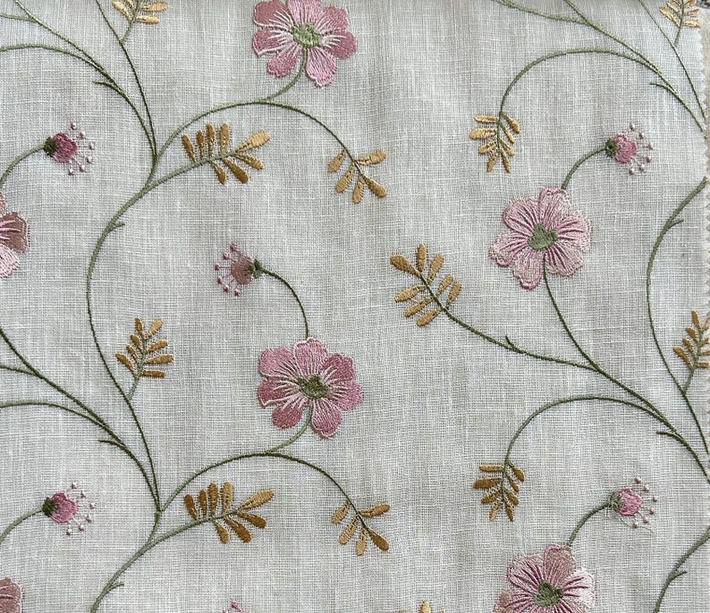 Puede incluir: Tela blanca con flores rosas y hojas doradas bordadas. El patr&oacute;n floral se repite en toda la tela.