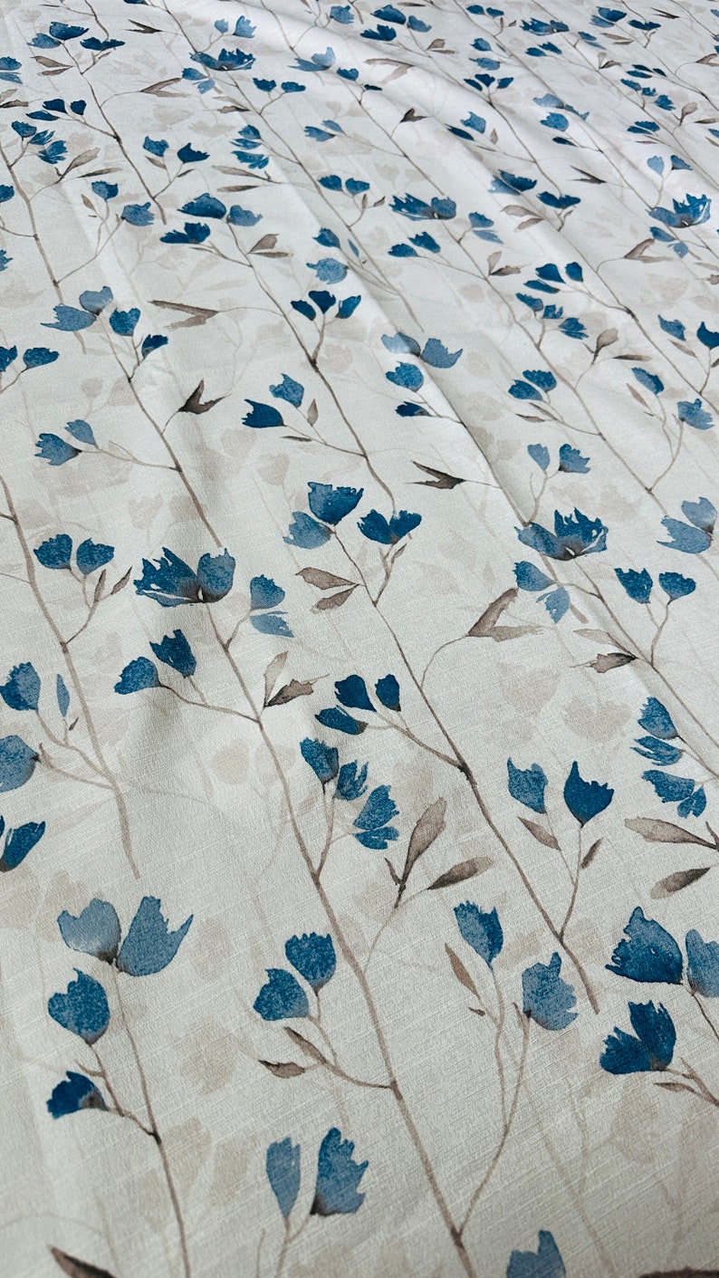 Pu&ograve; includere: Tessuto bianco con un motivo ripetitivo di fiori e steli blu ad acquerello.