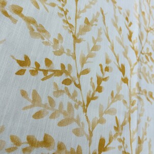 May include: White fabric with a subtle pattern of yellow leafy branches. The fabric has a linen-like texture.