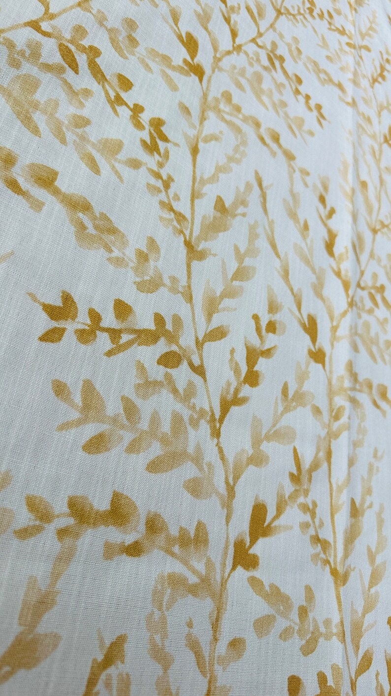 May include: White fabric with a subtle pattern of yellow leafy branches. The fabric has a linen-like texture.