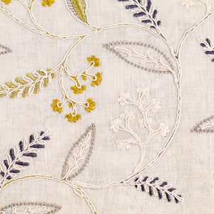 May include: White fabric with embroidered floral designs in shades of green, yellow, and purple.