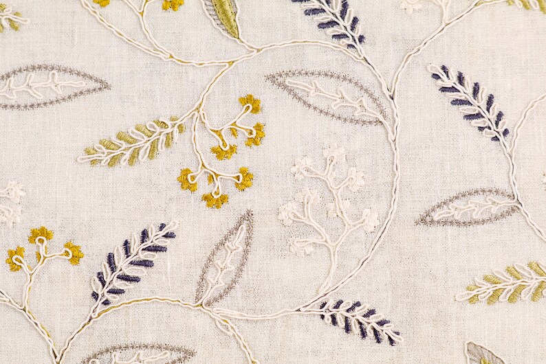 May include: White fabric with embroidered floral designs in shades of green, yellow, and purple.