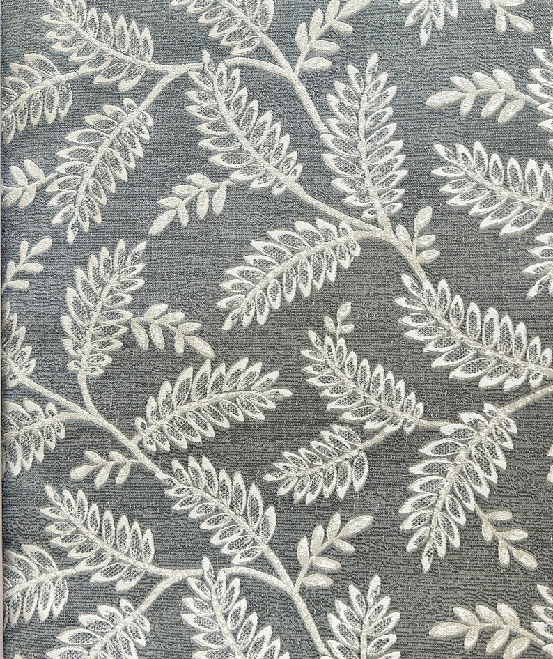 K&ouml;nnte beinhalten: Ein grauer Hintergrund mit einem wei&szlig;en Blumenmuster. Das Muster besteht aus zarten Zweigen und Bl&auml;ttern.
