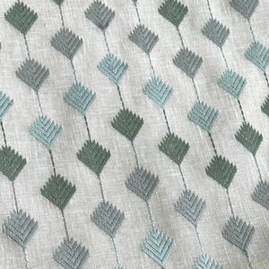 May include: A white fabric with a repeating pattern of green and blue diamond shapes. The diamonds are made of a textured fabric and are arranged in a diagonal pattern.