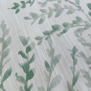 May include: White fabric with a green leafy pattern. The leaves are a muted green color and are printed on a white background.