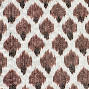 May include: A white fabric with a brown and black ikat pattern. The pattern is a repeating design of small, teardrop-shaped figures.