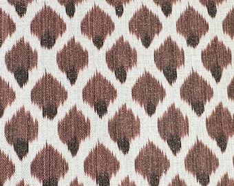 May include: A white fabric with a brown and black ikat pattern. The pattern is a repeating design of small, teardrop-shaped figures.