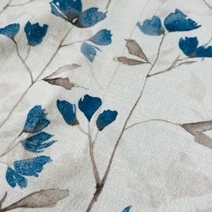 Pu&ograve; includere: Un tessuto bianco con un motivo floreale blu. I fiori sono stilizzati e ricordano acquerelli.