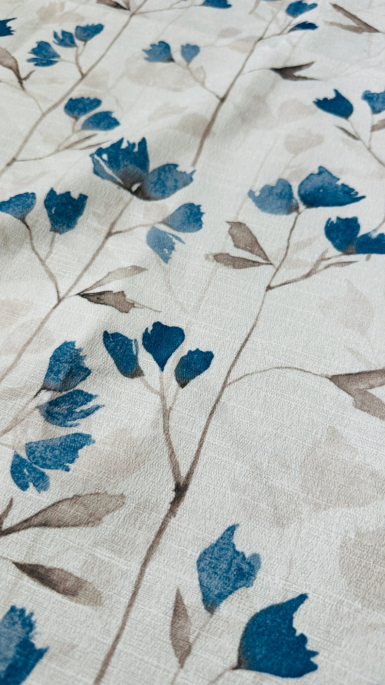 Pu&ograve; includere: Un tessuto bianco con un motivo floreale blu. I fiori sono stilizzati e ricordano acquerelli.
